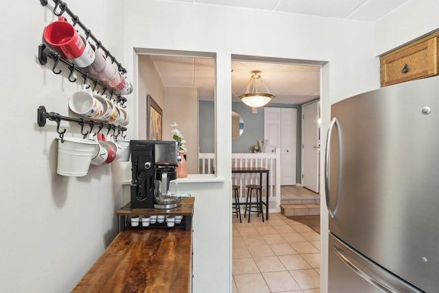 68 Pier Dr Unit 102, Westmont, IL 60559 - kitchen featuring freestanding refrigerator, light tile patterned floors, and brown cabinets