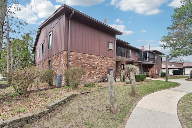 68 Pier Dr Unit 102, Westmont, IL 60559 - view of side of property with brick siding, a balcony, central AC unit, and a yard