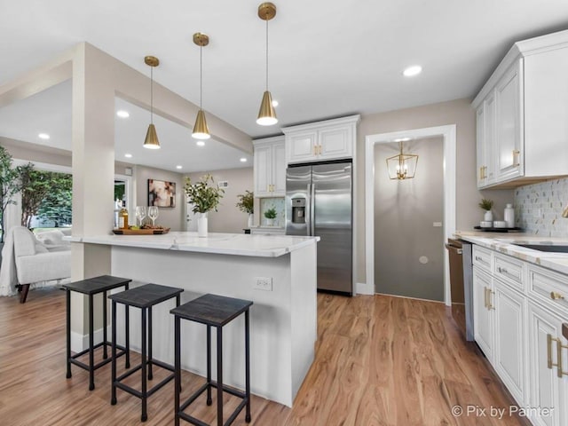 490 S Mchenry Ave, Crystal Lake, IL 60014 - kitchen with appliances with stainless steel finishes, tasteful backsplash, a breakfast bar, white cabinets, and light wood finished floors
