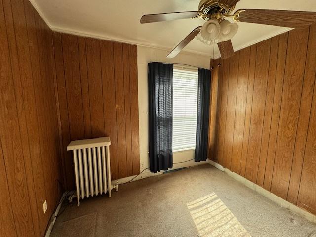 7952 S Elizabeth St, Chicago, IL 60620 - carpeted empty room featuring radiator heating unit, wooden walls, and ceiling fan
