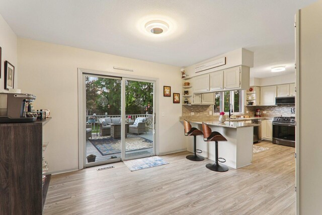 304 Fairhaven Dr, Winthrop Harbor, IL 60096 - kitchen featuring appliances with stainless steel finishes, open shelves, a breakfast bar area, and light wood-style floors