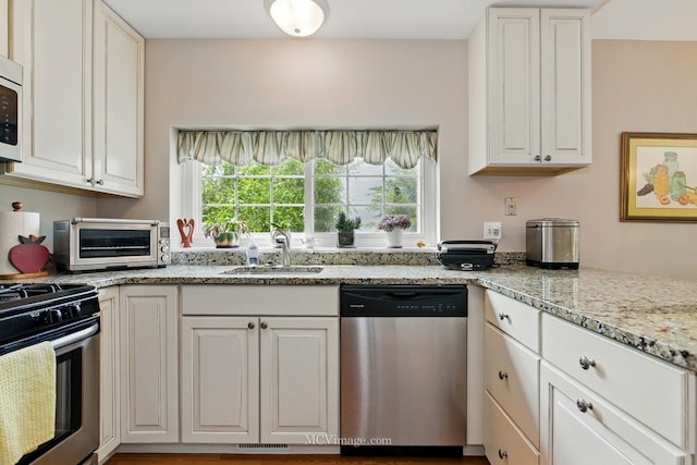 kitchen featuring appliances with stainless steel finishes, white cabinets, and light stone countertops