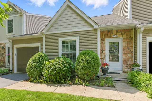 view of front of property with stone siding, roof with shingles, and driveway