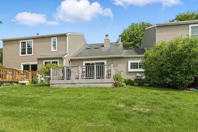 back of house with a wooden deck, a yard, and a chimney