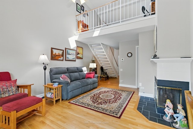 living area featuring stairway, wood finished floors, a towering ceiling, and a fireplace