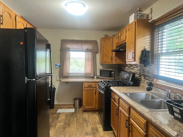 14701 E Riverside Dr, South Holland, IL 60473 - kitchen with black appliances, a sink, under cabinet range hood, light wood finished floors, and brown cabinets