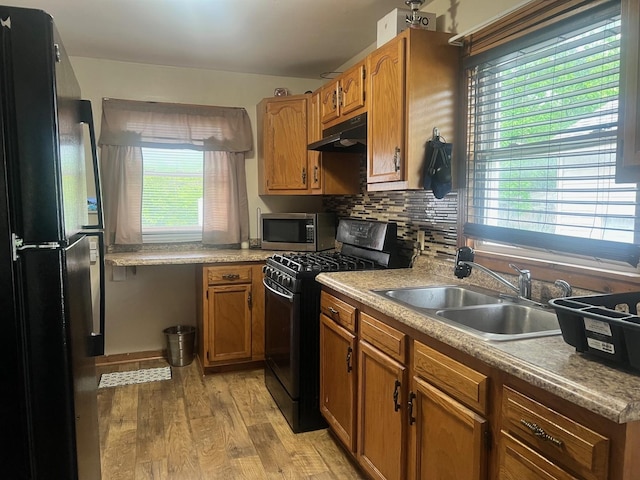 14701 E Riverside Dr, South Holland, IL 60473 - kitchen with black appliances, light wood-style flooring, a sink, under cabinet range hood, and brown cabinets