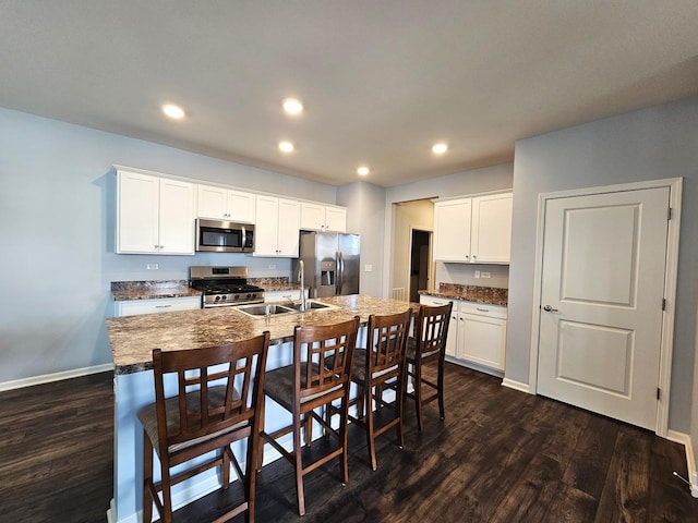 1847 Southern Cir, Pingree Grove, IL 60140 - kitchen featuring appliances with stainless steel finishes, dark wood-style flooring, a kitchen bar, a kitchen island with sink, and white cabinetry