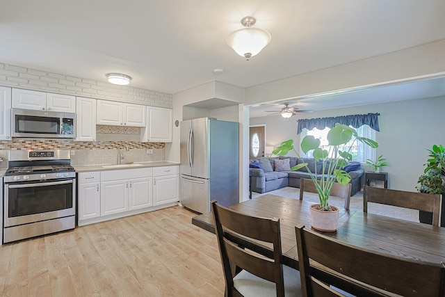 6124 Chase Ave, Downers Grove, IL 60516 - kitchen featuring stainless steel appliances, light countertops, white cabinetry, light wood-type flooring, and decorative backsplash