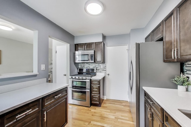 614 Beach Ave, La Grange Park, IL 60526 - kitchen with stainless steel appliances, light countertops, dark brown cabinets, light wood-style floors, and decorative backsplash