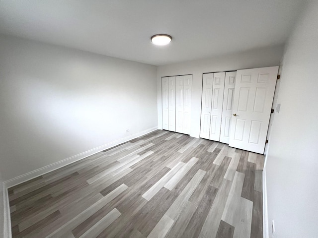 6842 W Lode Dr Unit 3B, Worth, IL 60482 - unfurnished bedroom with multiple closets, wood finished floors, and baseboards