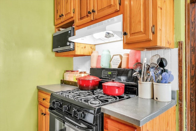 138 N Elm St, Paxton, IL 60957 - kitchen featuring range with gas cooktop, under cabinet range hood, stainless steel microwave, tasteful backsplash, and brown cabinetry