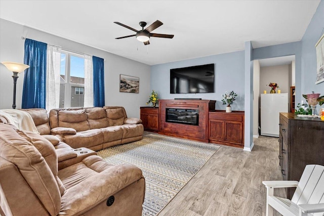 6904 Spruce Ct, Wonder Lake, IL 60097 - living room with a ceiling fan, light wood-style flooring, a glass covered fireplace, and baseboards