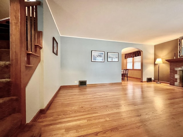 9214 S Sacramento Ave, Evergreen Park, IL 60805 - unfurnished living room featuring wood finished floors, crown molding, arched walkways, a brick fireplace, and baseboards