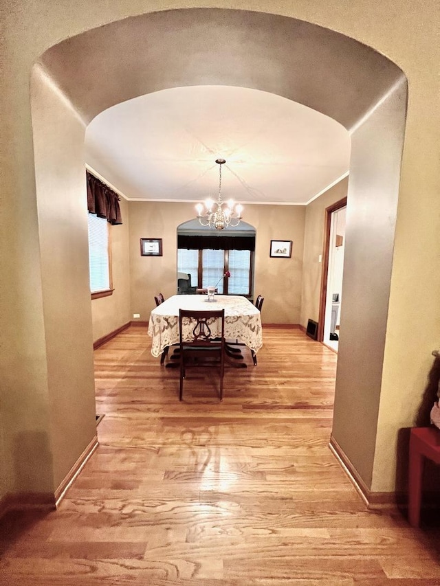 9214 S Sacramento Ave, Evergreen Park, IL 60805 - dining area with baseboards, a chandelier, light wood-style flooring, and arched walkways