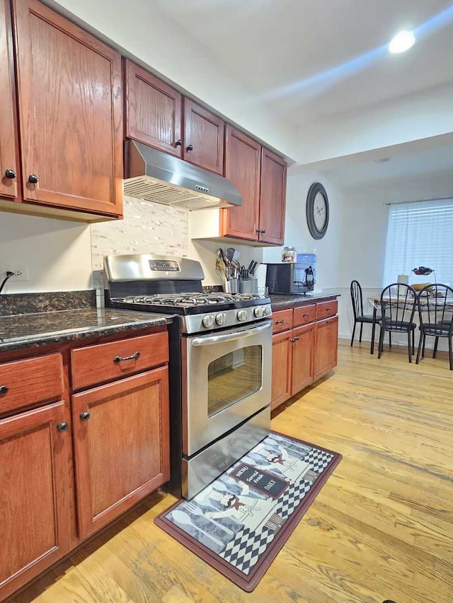 441 Commanche Trl, Wheeling, IL 60090 - kitchen with under cabinet range hood, stainless steel gas range, black microwave, light wood finished floors, and dark stone countertops