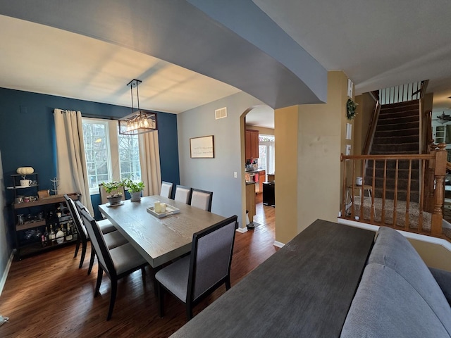3331 Banford Cir, Lake In The Hills, IL 60156 - dining area featuring stairway, dark wood-style floors, a chandelier, arched walkways, and baseboards