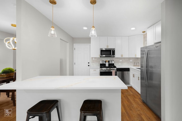 401 Monet Cir, Bolingbrook, IL 60440 - kitchen with appliances with stainless steel finishes, a breakfast bar area, wood finished floors, tasteful backsplash, and white cabinets