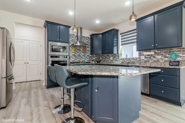 3751 Peregrine Way, Elgin, IL 60124 - kitchen with stainless steel appliances, wall chimney range hood, blue cabinetry, light wood-style flooring, and a kitchen breakfast bar