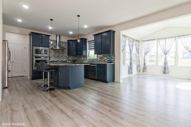 3751 Peregrine Way, Elgin, IL 60124 - kitchen with wall chimney range hood, appliances with stainless steel finishes, light wood-style floors, a breakfast bar, and decorative backsplash