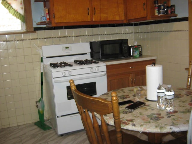 2339 N Kilbourn Ave, Chicago, IL 60639 - kitchen with gas range gas stove, black microwave, light countertops, brown cabinetry, and tile walls