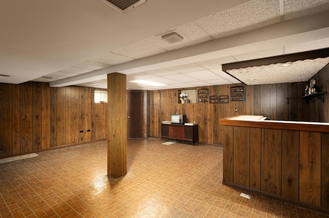 1128 N King Charles Ct, Palatine, IL 60067 - basement featuring wood walls, a paneled ceiling, bar, baseboards, and brick patterned flooring