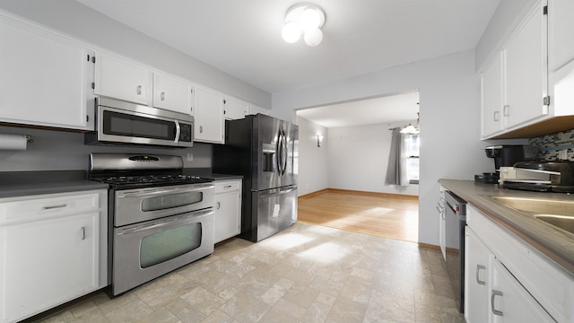 10129 Asbury Ln, Machesney Park, IL 61115 - kitchen with stainless steel appliances, white cabinets, and baseboards