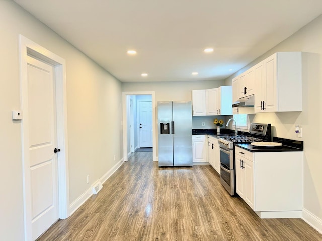 1327 N Pleasant Dr, Round Lake Beach, IL 60073 - kitchen featuring stainless steel appliances, under cabinet range hood, dark countertops, light wood finished floors, and recessed lighting