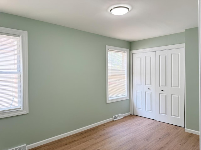 1327 N Pleasant Dr, Round Lake Beach, IL 60073 - unfurnished bedroom with baseboards, light wood finished floors, multiple windows, and a closet