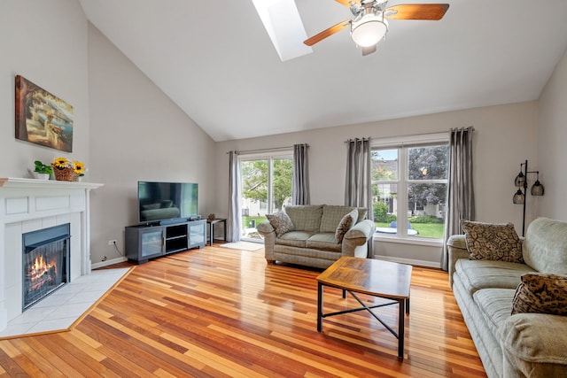 3502 Lake Side Cir, Joliet, IL 60431 - living area featuring light wood-style flooring, ceiling fan, a tile fireplace, a skylight, and high vaulted ceiling