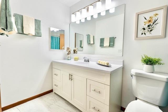 1413 N Metropolitan Ave, Waukegan, IL 60085 - bathroom with vanity, toilet, marble look tiles, and baseboards