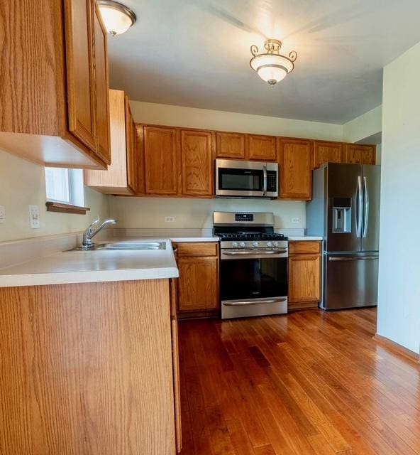 1413 N Metropolitan Ave, Waukegan, IL 60085 - kitchen featuring stainless steel appliances, a sink, dark wood finished floors, and brown cabinets