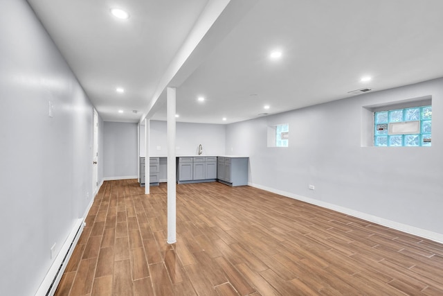 6210 N Francisco Ave, Chicago, IL 60659 - below grade area with a baseboard heating unit, wood finished floors, baseboards, recessed lighting, and healthy amount of natural light