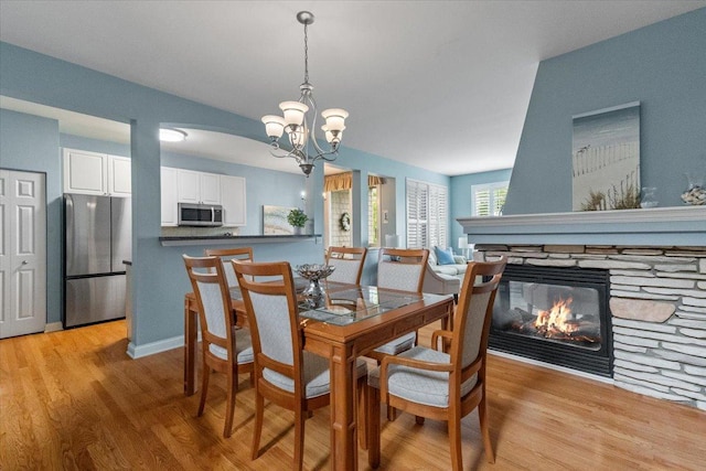 365 Lake Ave Unit D, Wauconda, IL 60084 - dining area with a chandelier, light wood-type flooring, and a stone fireplace