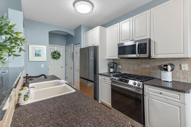 365 Lake Ave Unit D, Wauconda, IL 60084 - kitchen with appliances with stainless steel finishes, a sink, arched walkways, white cabinets, and tasteful backsplash