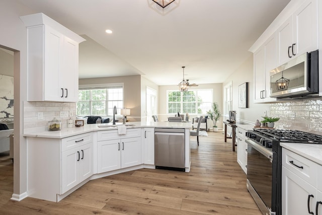 26615 W Captiva Ln, Plainfield, IL 60544 - kitchen featuring appliances with stainless steel finishes, a sink, a peninsula, tasteful backsplash, and light wood-style flooring