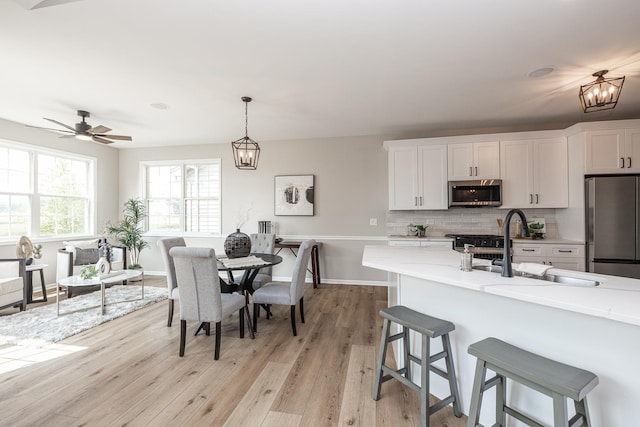 26615 W Captiva Ln, Plainfield, IL 60544 - kitchen with stainless steel appliances, light wood finished floors, a kitchen breakfast bar, decorative backsplash, and white cabinetry