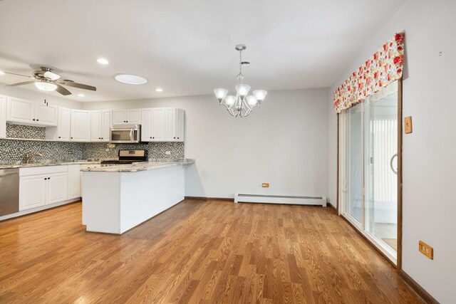 13116 Woodland Dr, Homer Glen, IL 60491 - kitchen featuring appliances with stainless steel finishes, a baseboard heating unit, decorative backsplash, white cabinetry, and plenty of natural light