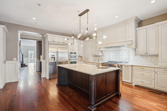 3926 N Greenview Ave, Chicago, IL 60613 - kitchen with stainless steel appliances, a sink, a chandelier, a center island with sink, and light stone countertops