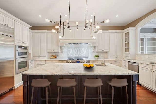 3926 N Greenview Ave, Chicago, IL 60613 - kitchen featuring appliances with stainless steel finishes, an island with sink, a chandelier, decorative backsplash, and a kitchen bar