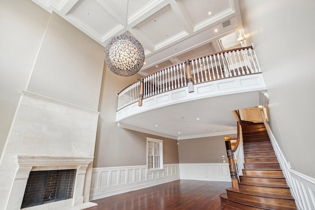 3926 N Greenview Ave, Chicago, IL 60613 - staircase featuring a high ceiling, a fireplace with raised hearth, a wainscoted wall, wood finished floors, and ornamental molding