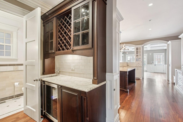 3926 N Greenview Ave, Chicago, IL 60613 - bar featuring wine cooler, decorative columns, arched walkways, backsplash, and dark wood finished floors
