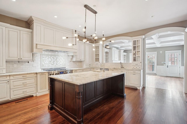 3926 N Greenview Ave, Chicago, IL 60613 - kitchen with a sink, coffered ceiling, glass insert cabinets, decorative backsplash, and a center island with sink