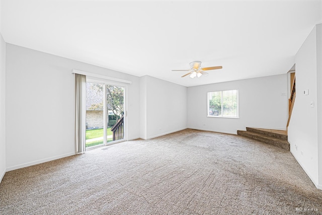carpeted spare room featuring ceiling fan and baseboards