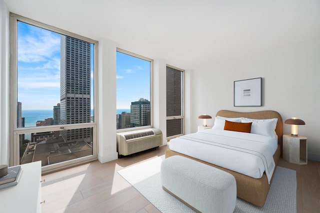 111 E Chestnut St Unit 40C, Chicago, IL 60611 - bedroom featuring wood finished floors, a water view, expansive windows, a wall mounted air conditioner, and a city view