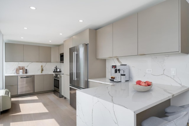 111 E Chestnut St Unit 40C, Chicago, IL 60611 - kitchen with appliances with stainless steel finishes, gray cabinets, decorative backsplash, light wood-style floors, and light stone counters