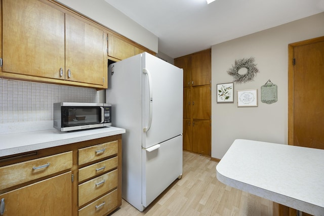 931 Sunset Rd, Wheaton, IL 60189 - kitchen featuring freestanding refrigerator, stainless steel microwave, light wood-style floors, backsplash, and light countertops