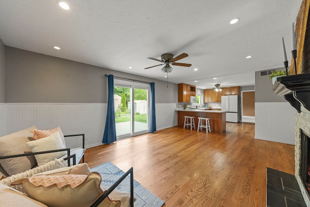 926 Navajo St, Carol Stream, IL 60188 - living area featuring a wainscoted wall, ceiling fan, recessed lighting, light wood-style flooring, and a fireplace with flush hearth