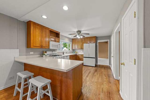 926 Navajo St, Carol Stream, IL 60188 - kitchen featuring white appliances, brown cabinets, light countertops, light wood-style flooring, and a peninsula