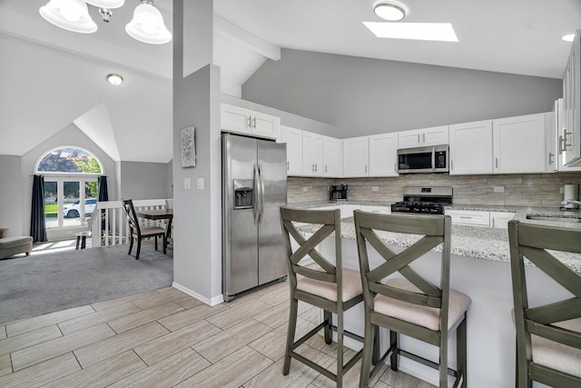 2825 Centurion Ln, New Lenox, IL 60451 - kitchen with appliances with stainless steel finishes, tasteful backsplash, white cabinetry, a breakfast bar area, and light stone countertops